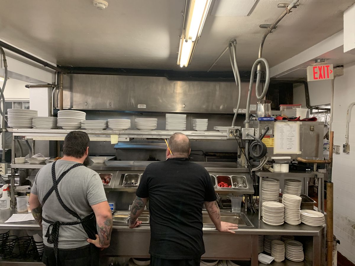 A stainless steel commercial restaurant kitchen, where fruit flies can breed around food prep and waste areas