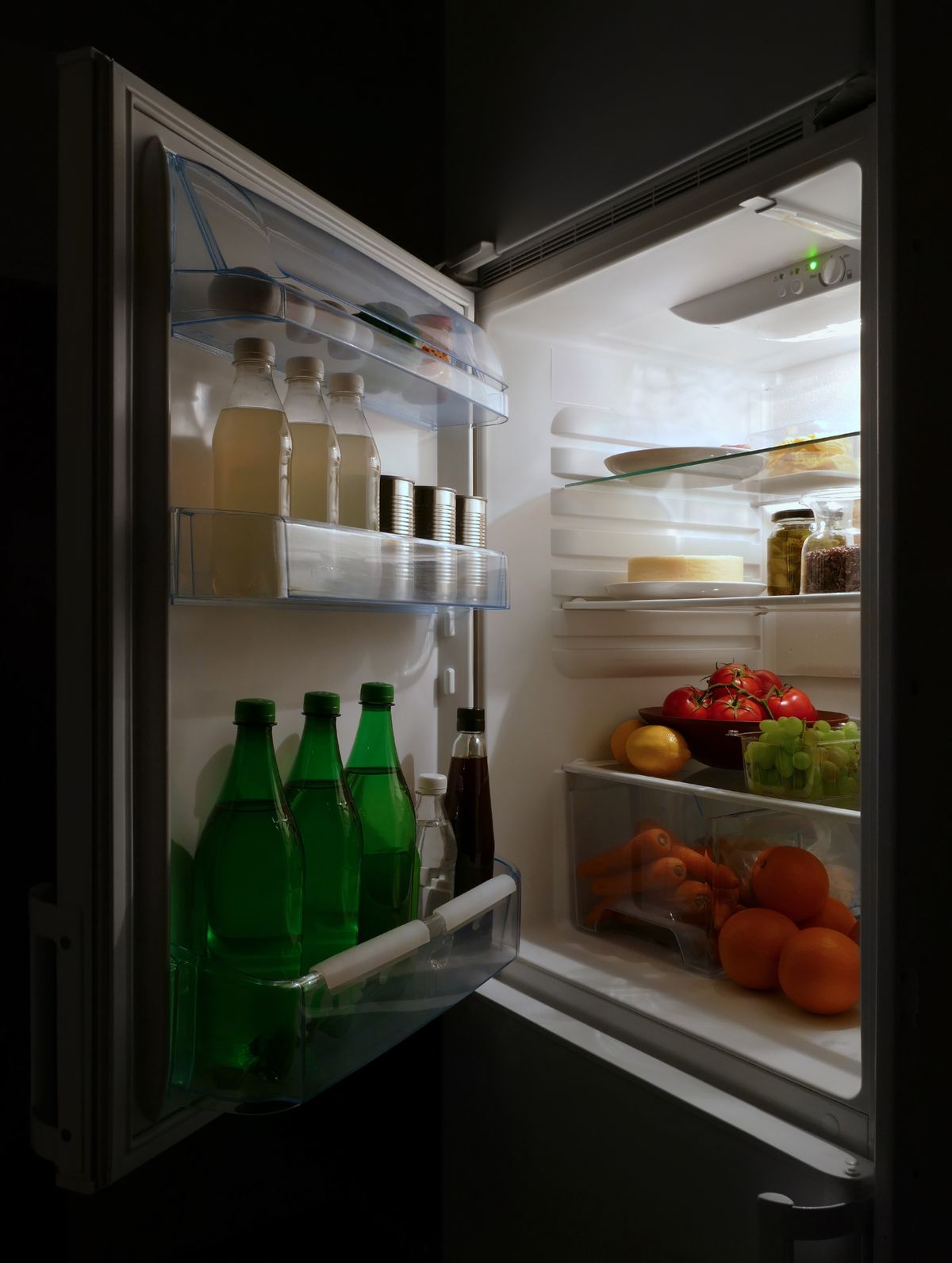An open refrigerator stocked with food; chilling ripe fruit and produce slows fermentation and keeps fruit flies from gathering