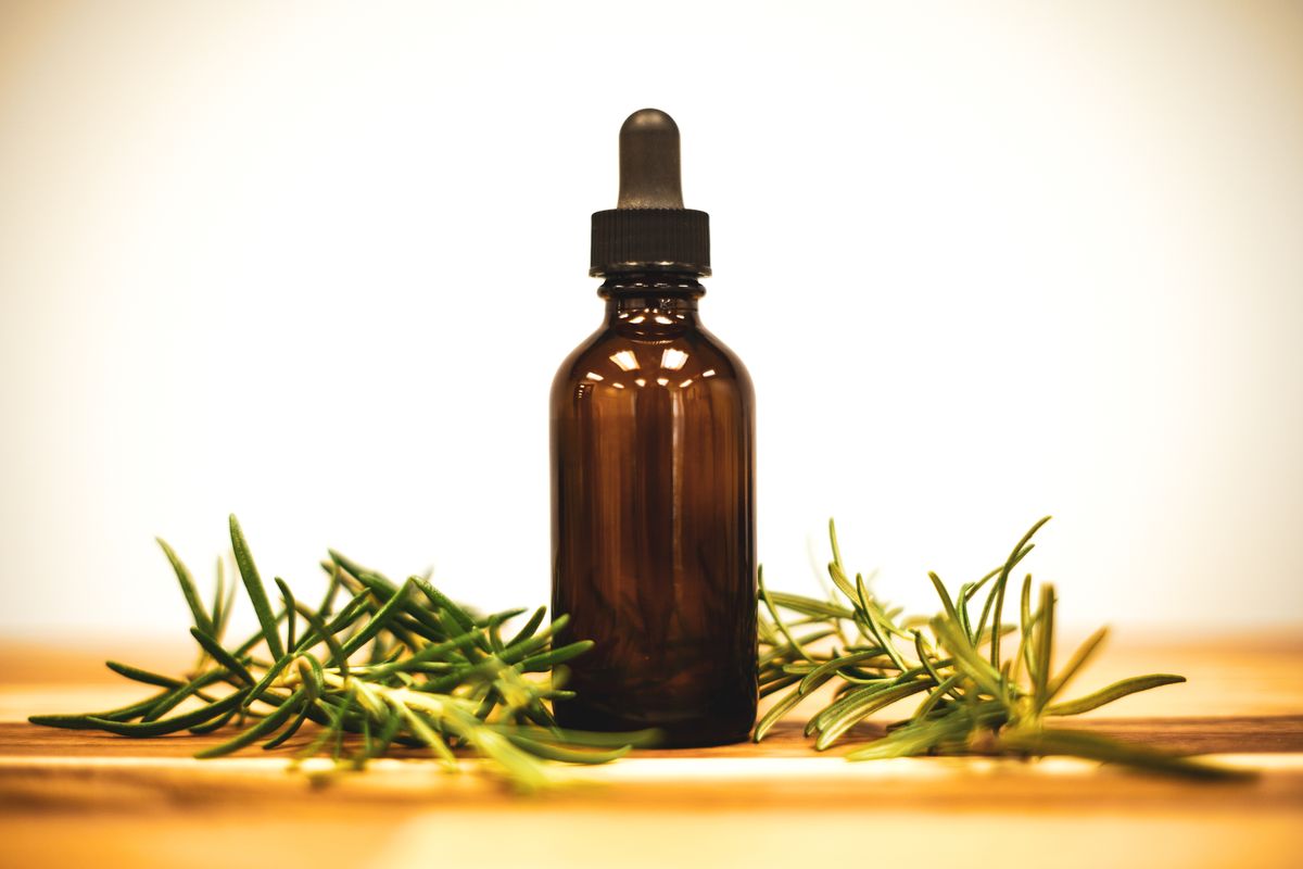 A bottle of essential oil beside fresh herbs; scents such as eucalyptus, peppermint and lemongrass are used to repel fruit flies